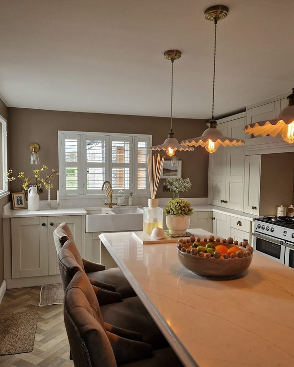 Kitchen with plantation shutters at the sink window and lit pendant lights over the island